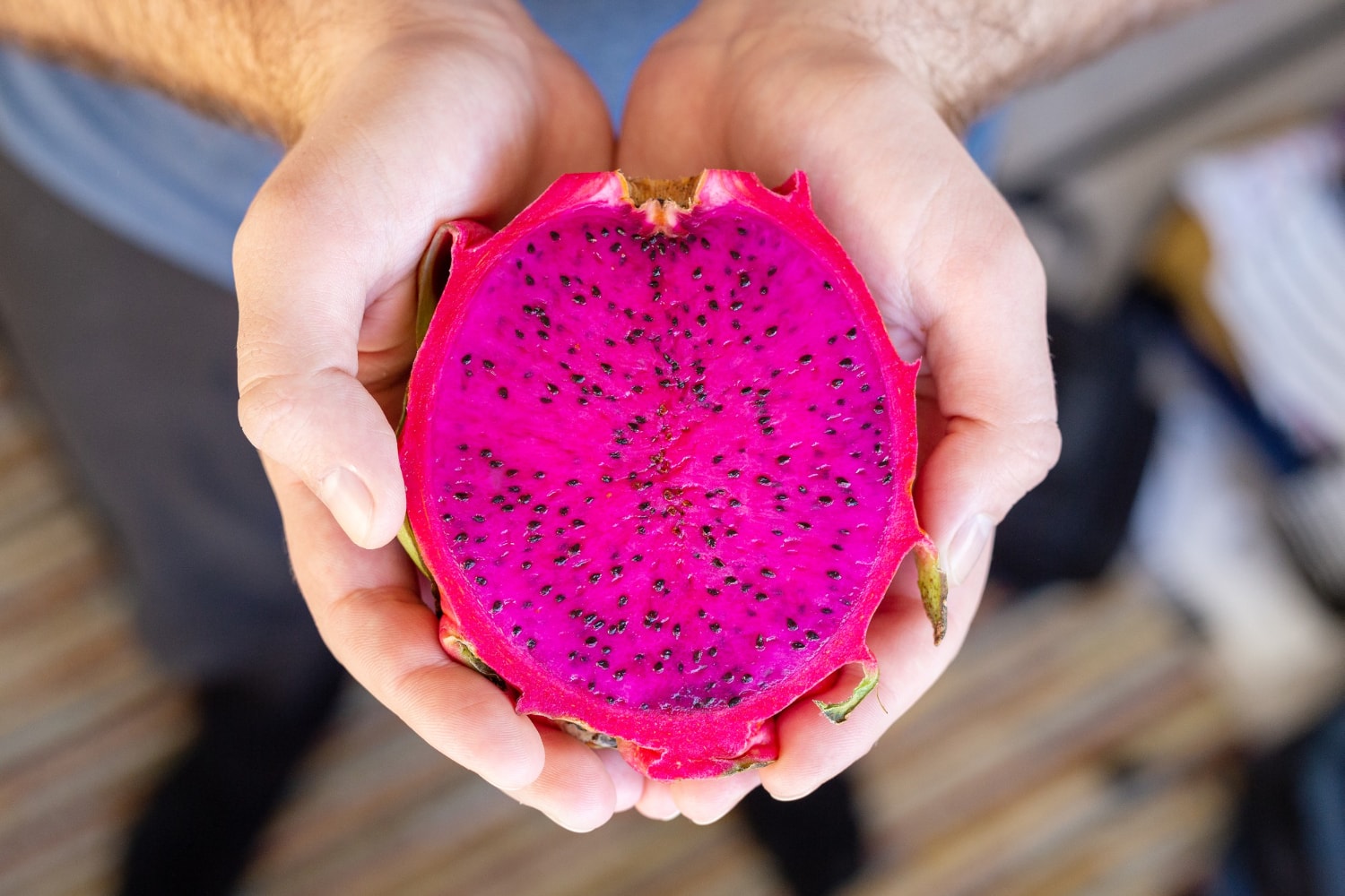 Manos sosteniendo media pitahaya de pulpa rosada